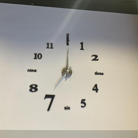 Uhr mit Zeigern, zeigt 7:00
12, 3, 6, 9 sind als Wort geschrieben (englisch), der Rest Ziffern
(Stazione Genova P. Principe)
