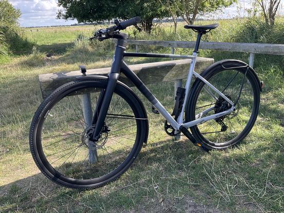 A black and silver bike leaning against a wooden bike stand.