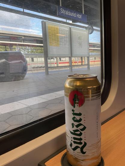 Dose Lübzer auf Fensterbank im RE, Blick aus dem Fenster auf Bahnhofschild Stralsund Hbf